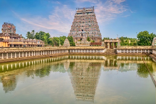 A famous South Indian Hindu temple, popular for religious pilgrimages, with traditional Dravidian architecture and a beautiful tower reflected in the water tank of the temple complex.