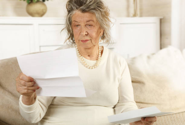 istock An old lady reading a letter sitting on a sofa 1205455167