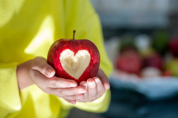 istock Red apple with heart symbol in girl's hand 1205455437