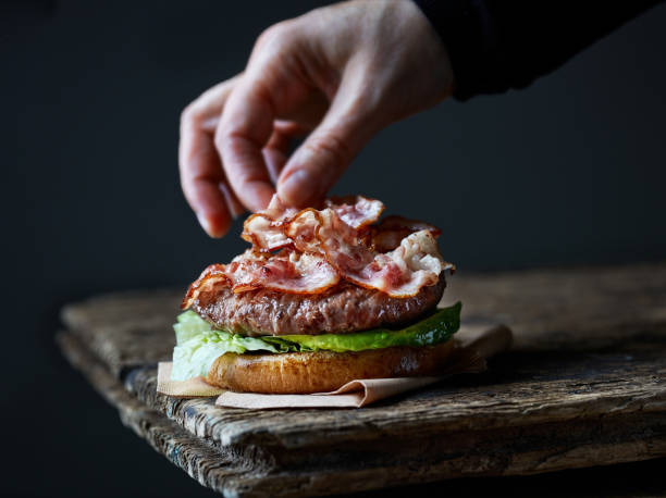 chef making burger with bacon - food styling imagens e fotografias de stock