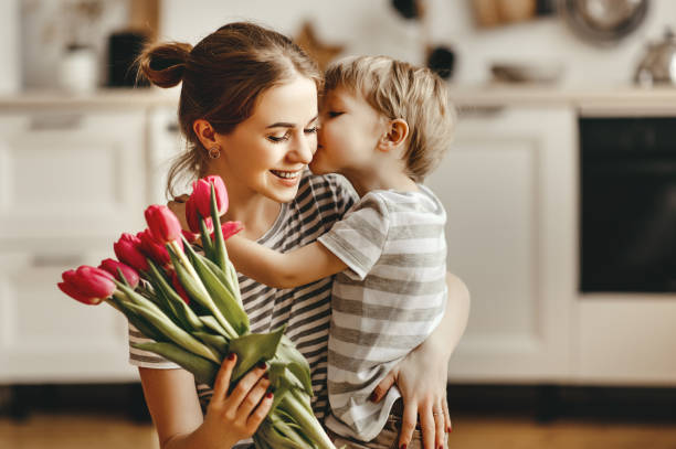 heureuse fête des mères! fils d’enfant donne des fleurs pour la mère en vacances - small bouquet photos et images de collection