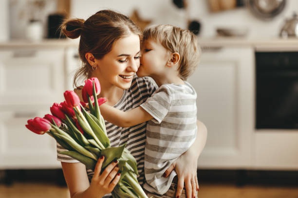 szczęśliwy dzień matki! dziecko syn daje kwiaty dla matki na wakacjach - mother love zdjęcia i obrazy z banku zdjęć