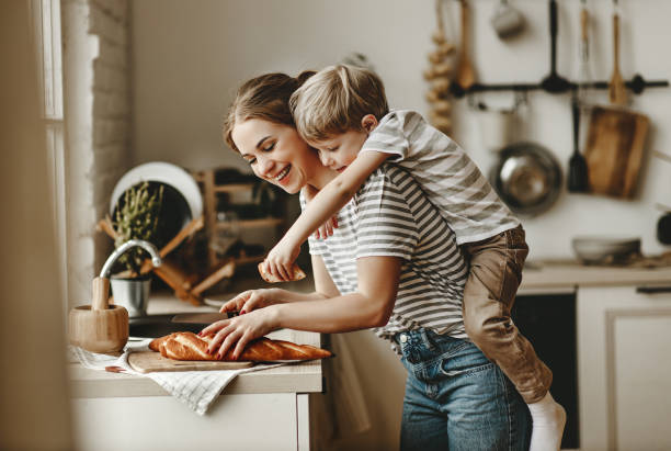 preparation of family breakfast. mother and child son cut bread   in morning - family mother domestic life food imagens e fotografias de stock