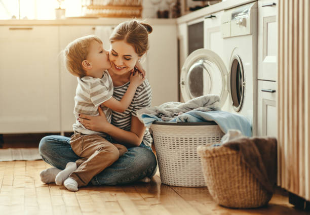 szczęśliwa matka rodzinna gospodyni domowa i dziecko w pralni z pralką - stereotypical housewife little girls family domestic kitchen zdjęcia i obrazy z banku zdjęć