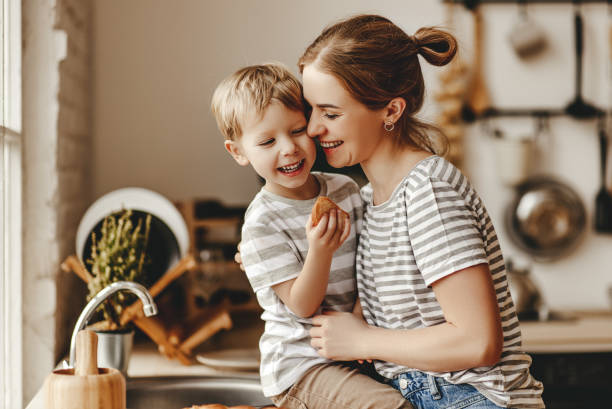 家族の朝食の準備。母と子の息子は朝にパンを切り、ミルクとクッキーを食べる - mother son family cooking ストックフォトと画像