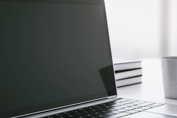 istock Closeup of blank laptop screen on a white table with cup of coffee. 3D Rendering 1205459600