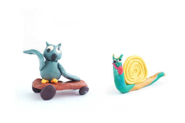 istock Cartoon plasticine figure owl on a skateboard and a plasticine snail. Isolate on a white background. 1205459683