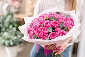 Lots of buds Roses of pink fuchsia color. Bouquet in woman hand. the work of the florist at a flower shop Flower shop concept
