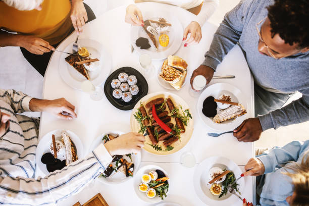 istock Top view of five multicultural friends sitting at dinning table and having healthy lunch. 1205465732