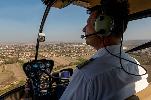 Pilot with headphones flying over residential district and fields in the plain area