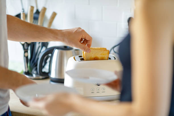 Close-up of man's hand taking toasting bread out of toaster