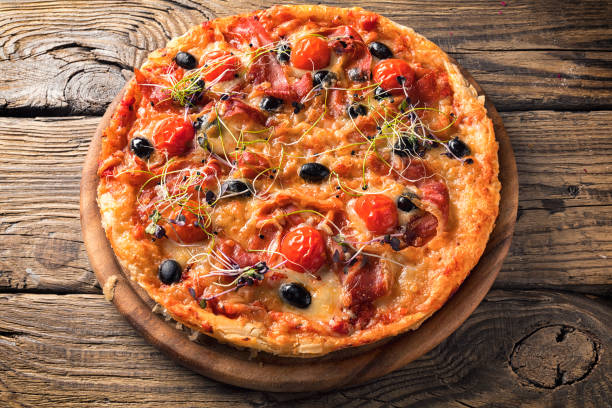 istock Delicious pizza served on wooden plate 1205467937