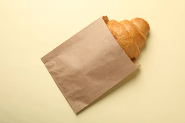 istock Craft paper bag with croissant on beige background, space for text 1205469414