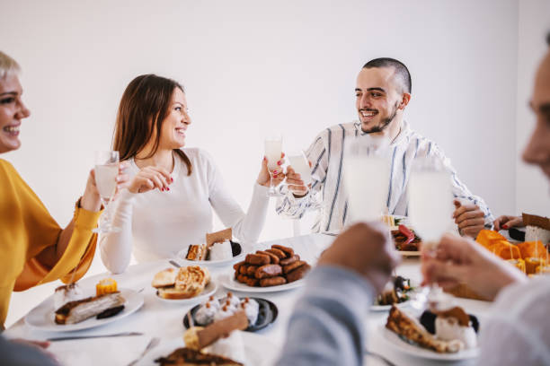 istock Group of multicultural friends sitting at dinning table for lunch and toasting with fresh lemonade. 1205470274
