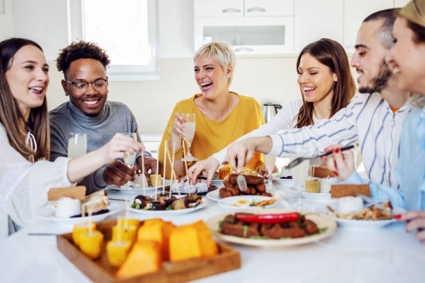 istock Group of happy multicultural friends sitting at dinning table at home, drinking fresh lemonade, eating healthy lunch, chatting and laughing. 1205470423