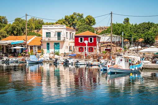 Colorful and picturesque image with buildings and small fishing boats in the marina of Mithymna, Lesbos Islands. A beautiful summer day with blue sky.