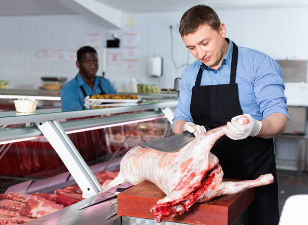 istock Skillful butcher processing carcase of young lamb for sale at butchery 1205473464