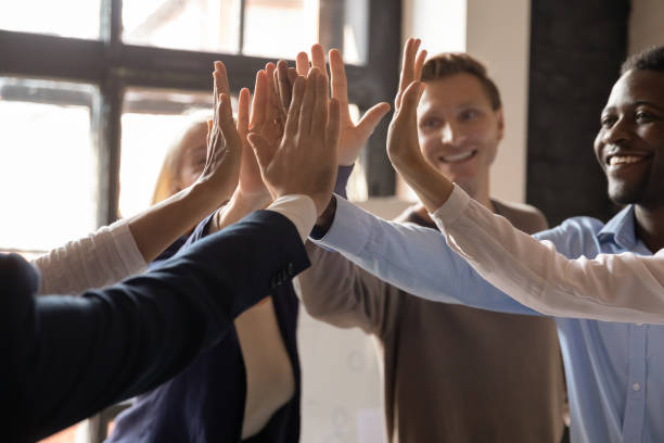 istock Closeup different ethnicity businesspeople raised hands giving high five 1205475145
