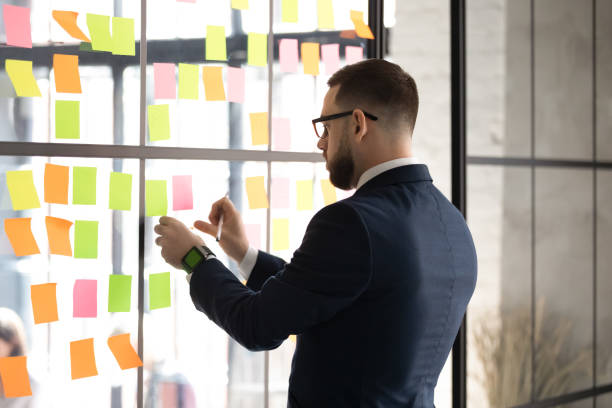 istock Businessman prepare boardroom for negotiations attaching post-it on wall 1205475200