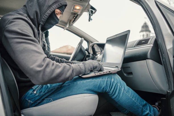 złodziej samochodów rozbrajając zabezpieczenia samochodu za pomocą laptopa - computer hacker identity security stealing zdjęcia i obrazy z banku zdjęć