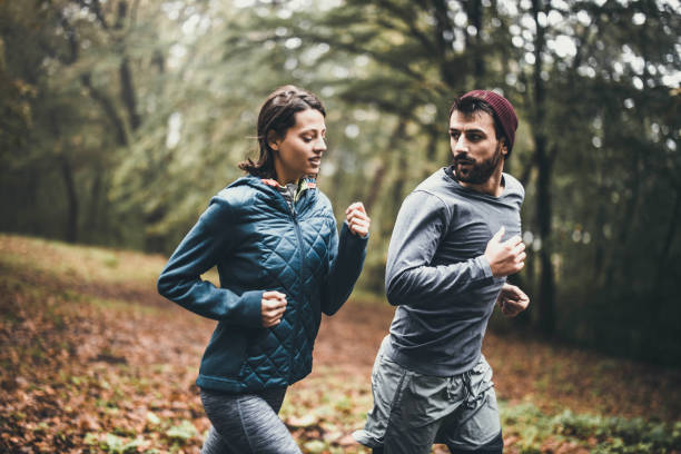 istock Young athletic couple jogging during autumn day in nature. 1205477857