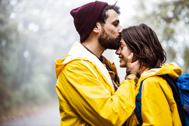 Happy affectionate couple in raincoats enjoying in nature.