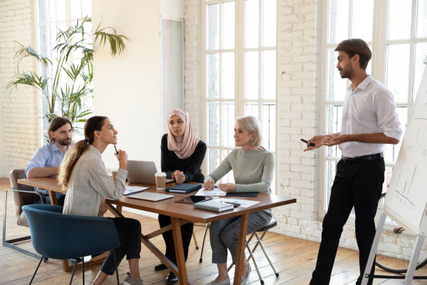 istock Male coach making flip chart presentation for multiracial colleagues 1205480380