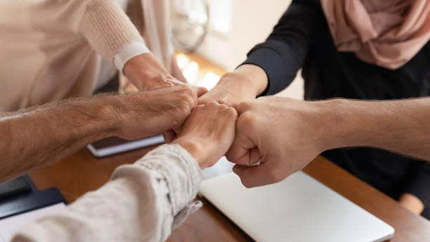 istock Close up of diverse employees join hands show unity 1205480483