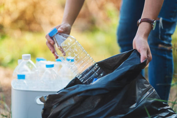 istock A woman picking up garbage plastic bottles into a bin and bag 1205480594