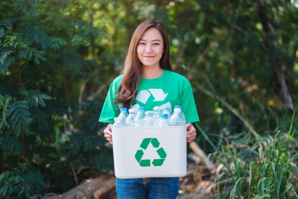 istock A woman collecting garbage and holding a recycle bin with plastic bottles 1205480595