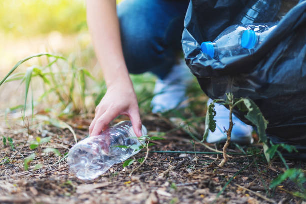 istock a woman picking up garbage plastic bottles into a trash bag 1205480609
