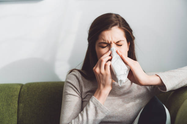 istock Woman suffering for allergies blowing her nose 1205482694