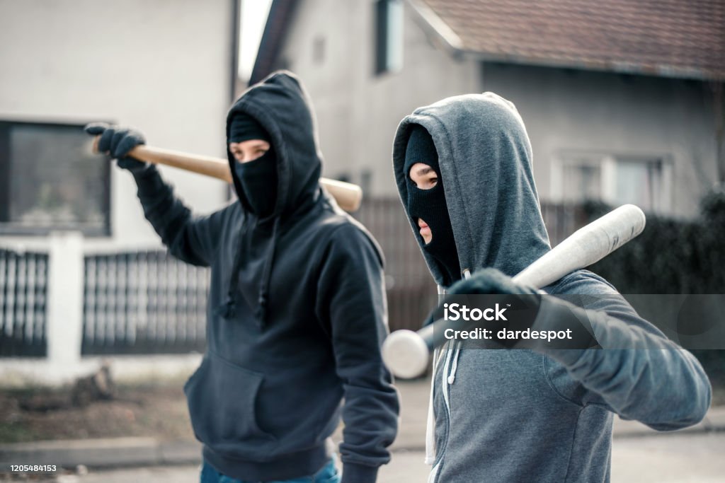 Young men holding a baseball bat symbolizing crime Baseball Bat Stock Photo
