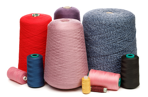 Cones and spools of synthetic or cotton threads on white background. Spool of yarn using for weaving in textile manufacturing