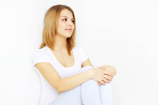 Pretty young lady sitting on the floor on light background