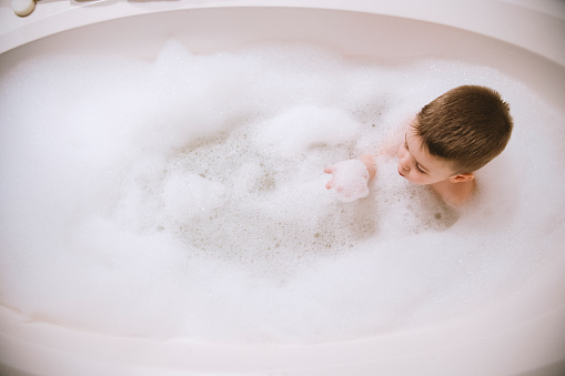 Boy in the bathtub playing with toys