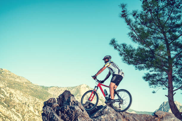 in sella alla mountain bike su una pista rocciosa contro il cielo blu. - journey footpath exercising effort foto e immagini stock