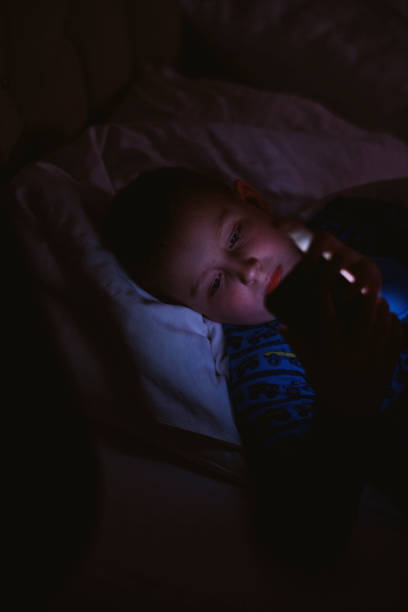 istock Boy lying on bed with smart phone 1205489712