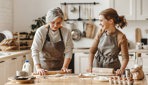 abuela de la familia feliz vieja suegra y hija de la nuera cocinar en la cocina, amasar la masa, hornear galletas - baking lifestyles beautiful cookie fotografías e imágenes de stock