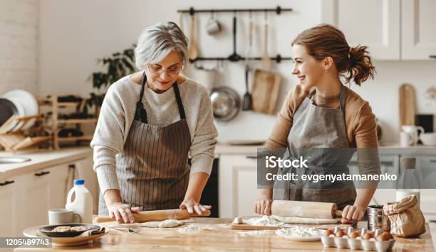 Happy Family Grandmother Old Mother Motherinlaw And Daughterinlaw Daughter Cook In Kitchen Knead Dough Bake Cookies Stock Photo - Download Image Now