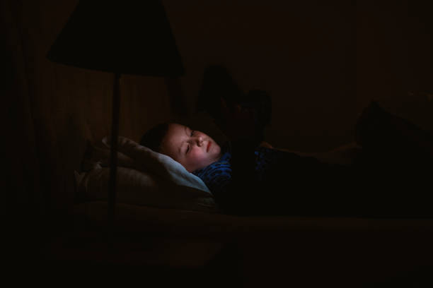 istock Boy lying on bed with smart phone 1205490484