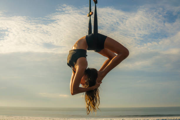 aero yoga beach workout - young attractive and athletic woman practicing aerial yoga exercise training acrobatic body postures on blue sky over sea in Bali island healthy lifestyle concept entrenamiento de playa de yoga aero - joven atractiva y atlética mujer que practica ejercicio de yoga aéreo entrenamiento de posturas del cuerpo acrobático en el cielo azul sobre el mar en la isla de bali concepto de estilo de vida saludable