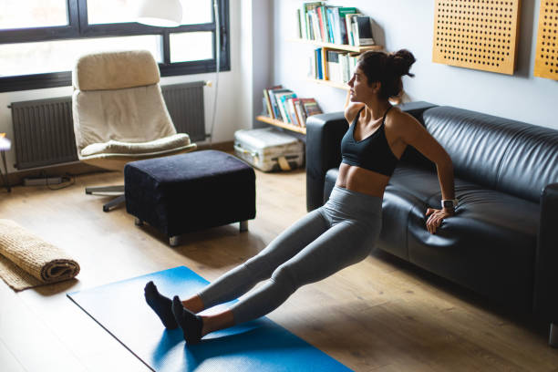 Young fit woman exercising at home Fitness workout at home. Healthy fit young woman doing triceps dips exercise in the living room. home workout stock pictures, royalty-free photos & images