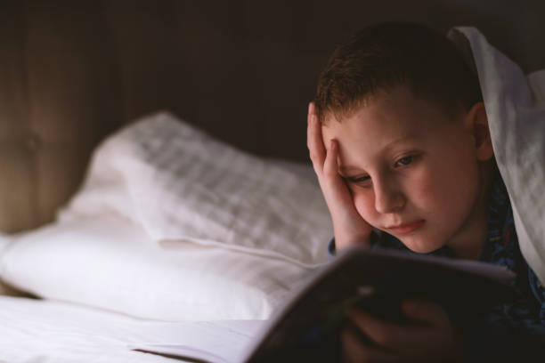 istock Little boy reading book in bed 1205492702