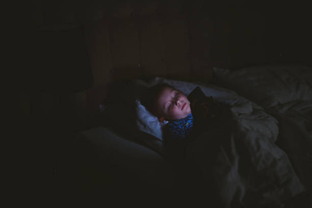istock Boy lying on bed with smart phone 1205492741