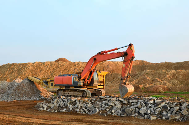 istock Heavy tracked excavator load stone, old asphalt or concrete waste into a mobile jaw crusher machine 1205492831