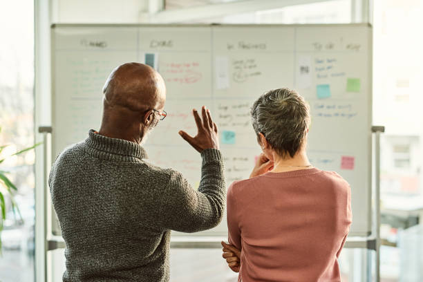 We can really grow the business this way Cropped shot of two unrecognizable businesspeople standing together and using a white board during a discussion in the office whiteboard visual aid photos stock pictures, royalty-free photos & images