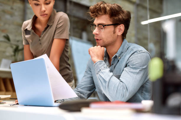 istock Together we can do so much. Young colleagues looking at document and discussing something while working together in the creative office 1205495720