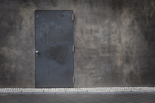 Closed steel door and grungy concrete wall with vignette.