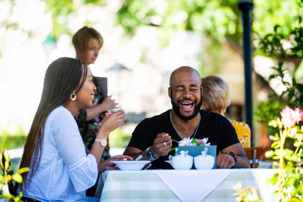 istock Laughing Couple on a restaurant veranda having a meal smiling with eyes closed 1205497326